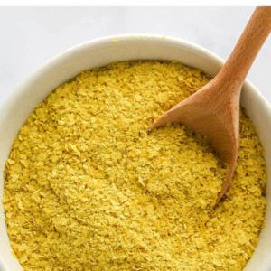 Bowl of nutritional yeast with a wooden spoon in the bowl.