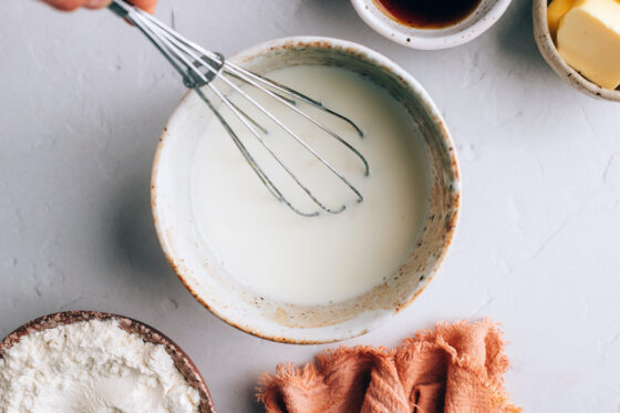Almond milk and vinegar being whisked in a small bowl.