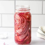 A glass jar with picked red onions.