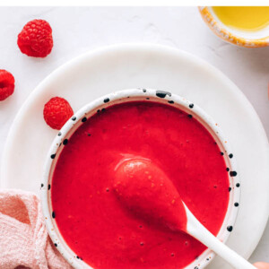Spoon dipped in a bowl of raspberry vinaigrette dressing.