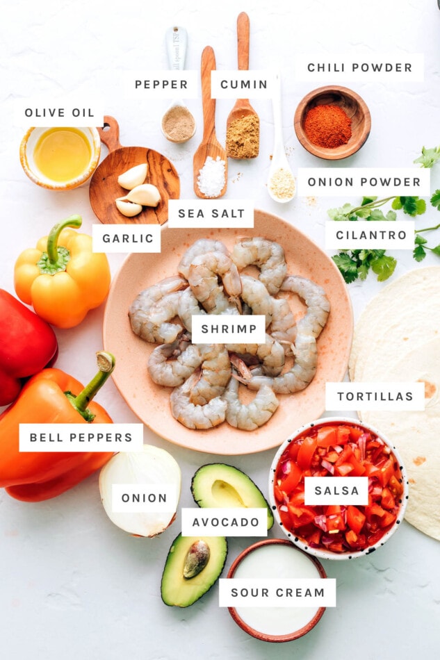 These sheet pan shrimp fajitas make for an easy weeknight meal with Mexican flavor. Simply bake your shrimp, peppers and onions together on one sheet, load up your tortillas and enjoy! Ingredients measured out to make shrimp fajitas: pepper, cumin, chili powder, onion powder, olive oil, sea salt, garlic, cilantro, shrimp, tortillas, bell peppers, onion, avocado, salsa and sour cream.