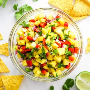 Pineapple salsa in a serving bowl with chips scattered around.