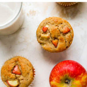 Overhead view of apple yogurt muffins scattered around with an apple.