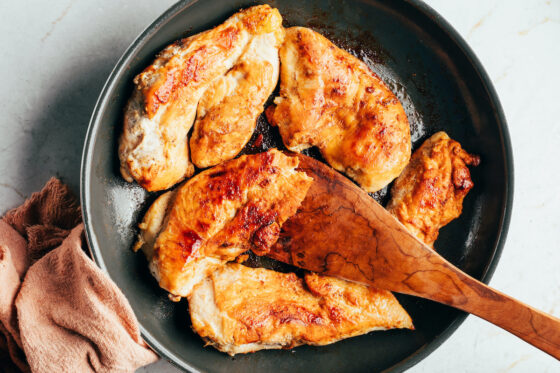 Multiple cooked and seasoned chicken thighs in a large skillet.