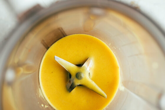 A golden/yellow dressing blended in a blender.