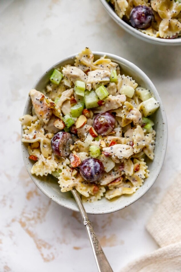 A bowl containing poppyseed chicken pasta salad with a spoon.