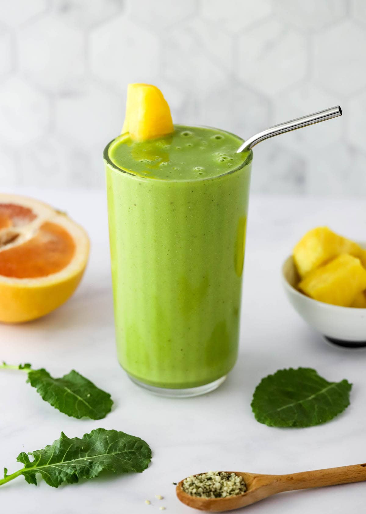 A glass containing vitamin c smoothie. It's topped with a wedge of pineapple and a straw.