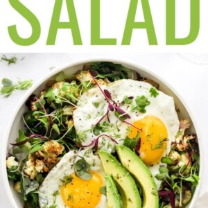 Salad topped with sunny-side-up eggs and avocado.