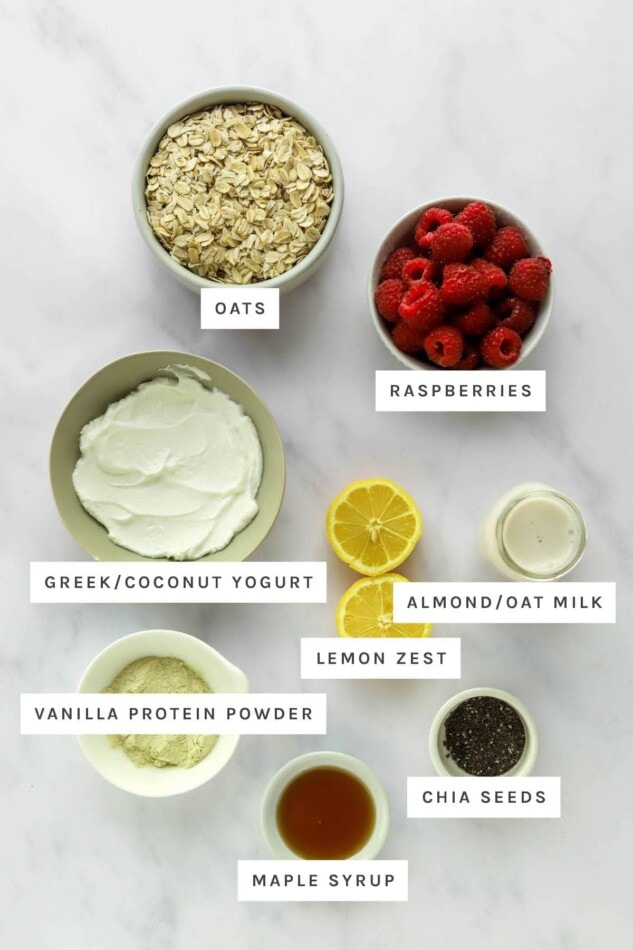 Ingredients measured out to make Raspberry Lemon Overnight Oats: oats, raspberries, yogurt, milk, lemon zest, vanilla protein powder, chia seeds and maple syrup.