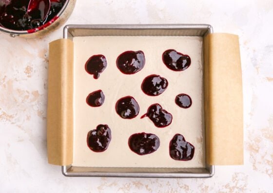 Dollops of blueberry sauce added to square baking pan.