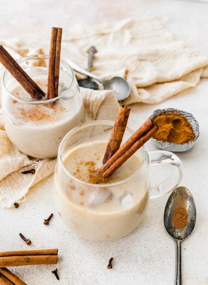 A healthier take on festive holiday eggnog, this clean eating eggnog uses almond and coconut milk, egg whites and pure maple syrup. It's lighter in calories and dairy-free but still just as delicious as real deal nog. Two glasses of dairy free eggnog with cinnamon sticks.