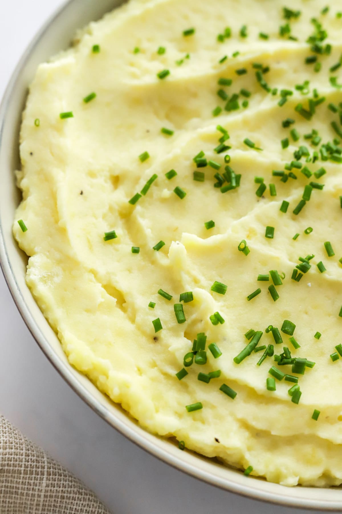 A bowl of mashed potatoes garnished with fresh chives.