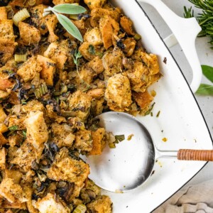 Sourdough stuffing in a serving dish with a serving spoon.