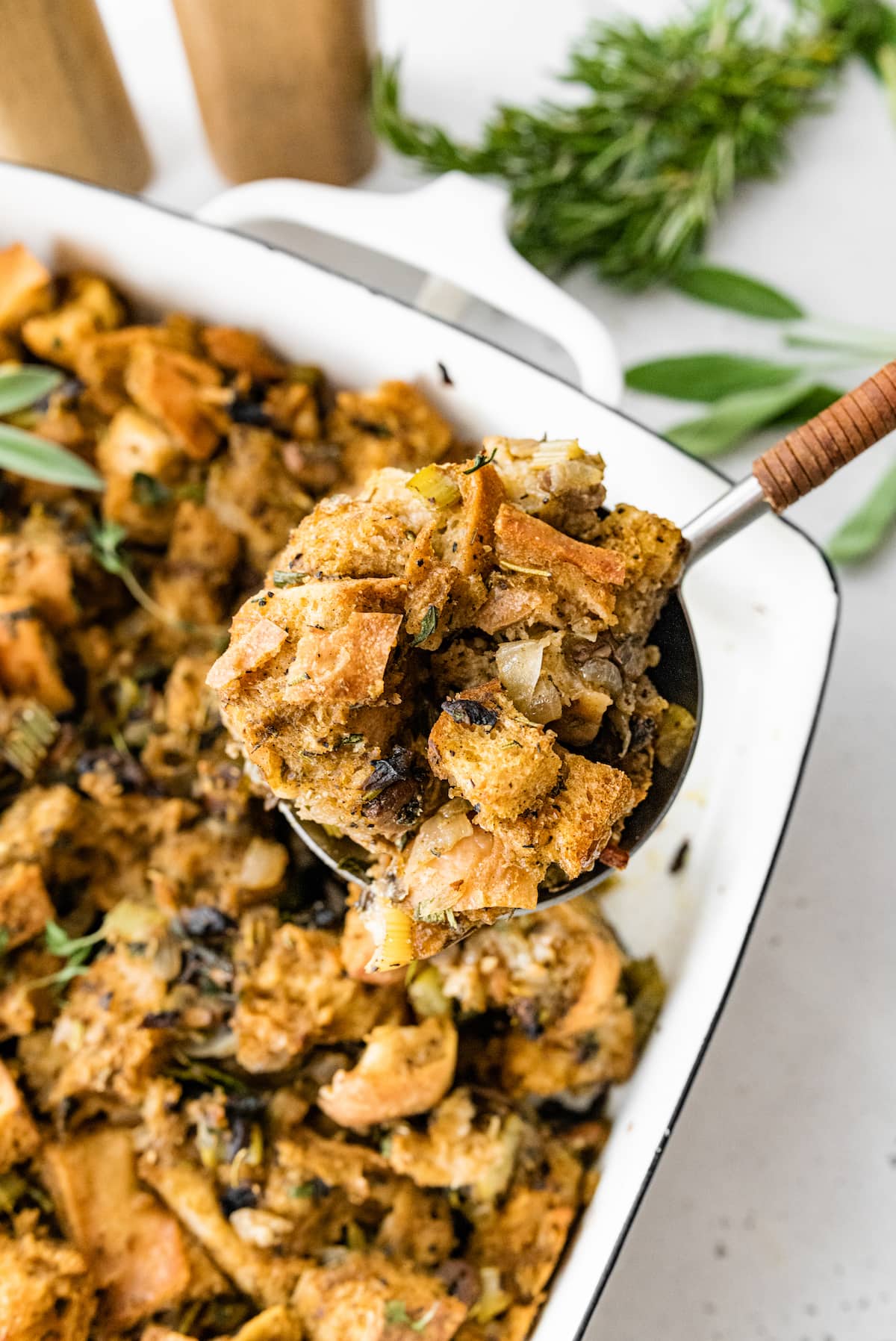 A spoonful of vegan sourdough stuffing over a baking dish.