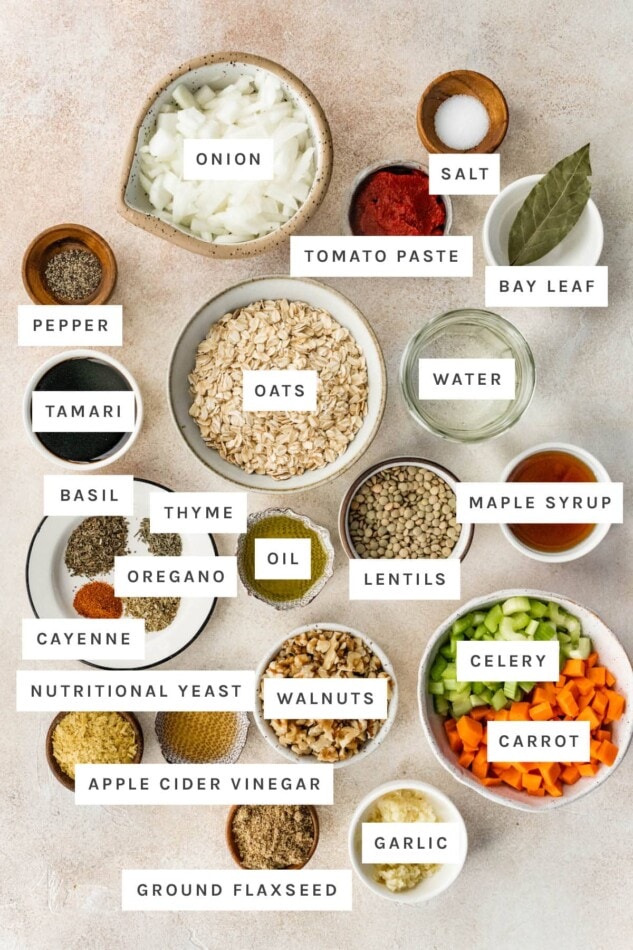 Ingredients measured out to make Lentil Meatballs: onion, salt, tomato paste, bay leaf, pepper, oats, tamari, water, basil, thyme, oregano, cayenne, oil, lentils, maple syrup, nutritional yeast, walnuts, celery, carrots, vinegar, ground flaxseed and garlic.
