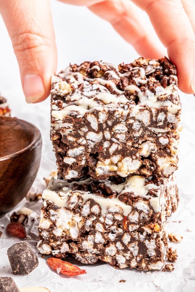 A hand grabbing a crisphy chocolate rice cake bar crunch bar from a stack.