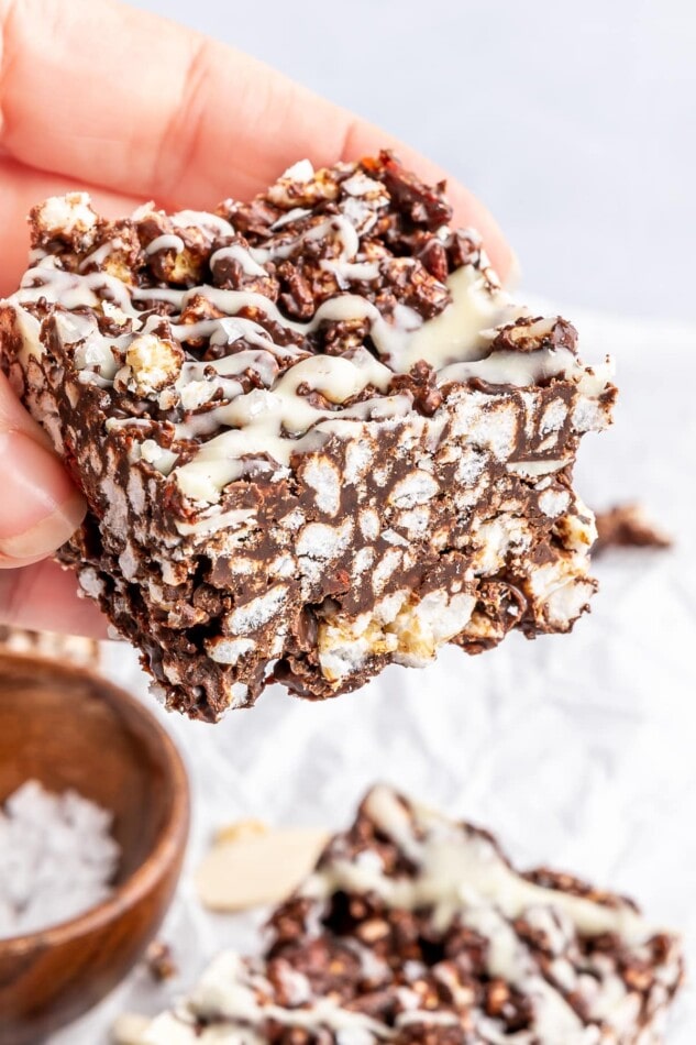 A hand holding a crispy chocolate rice cake bar.