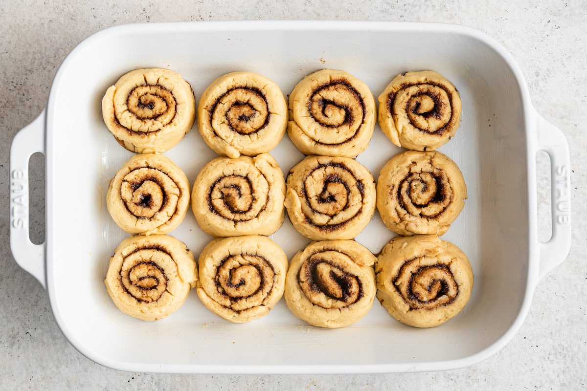 Cinnamon rolls placed 3 by 4 in a baking dish.