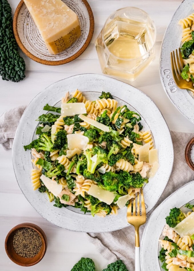Tuna, broccoli and kale caesar pasta salad on a plate topped with shaved parmesan