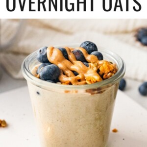 A jar of blended overnight oats topped with blueberries, nut butter and granola.