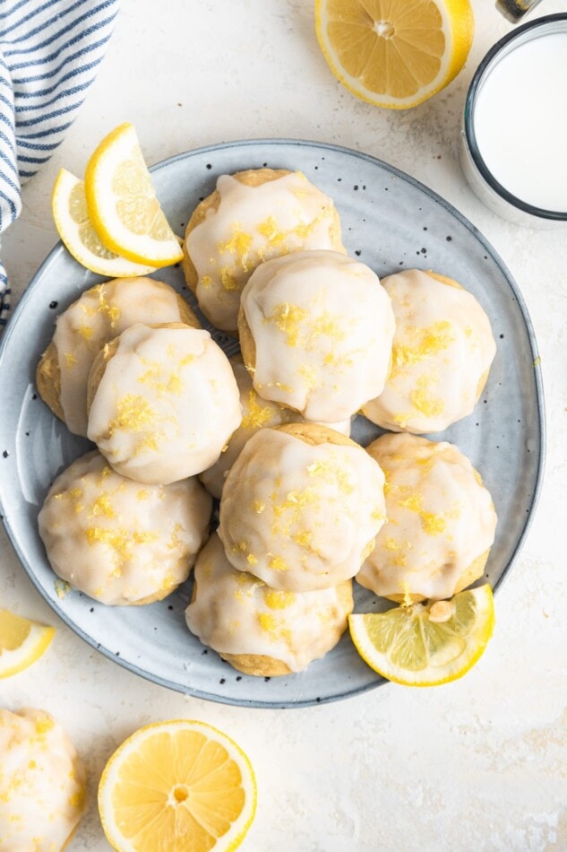 Lemon ricotta cookies on a plate with lemon wedges.