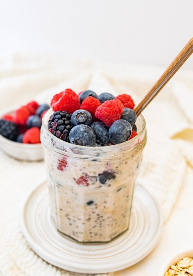 A jar of low calorie overnight oats topped with fresh mixed berries.