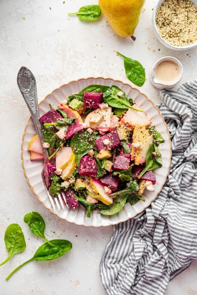 A serving of pear and beet salad on a plate with a fork.