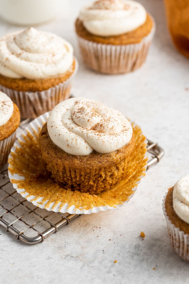 An unwrapped frosted sweet potato cupcake.
