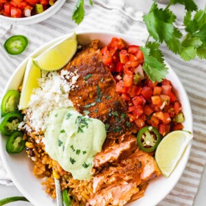 Salmon burrito bowl topped with avocado crema.