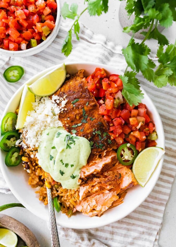 Salmon burrito bowl topped with avocado crema.