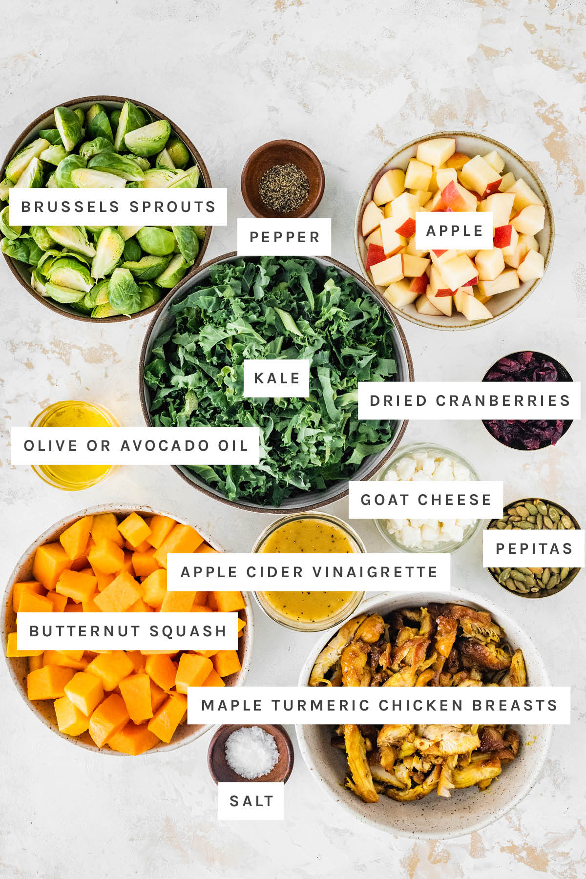 Ingredients measured out to make Harvest Bowls: brussels sprouts, pepper, apple, kale, dried cranberries, olive oil, goat cheese, vinegar, pepitas, butternut squash, maple turmeric chicken breasts and salt.