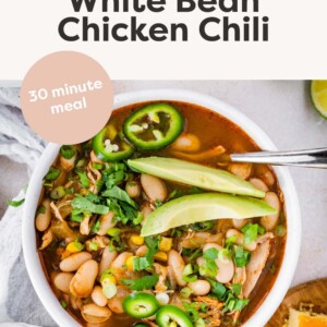 A bowl of white bean chicken chili topped with jalapeño slices and avocado.