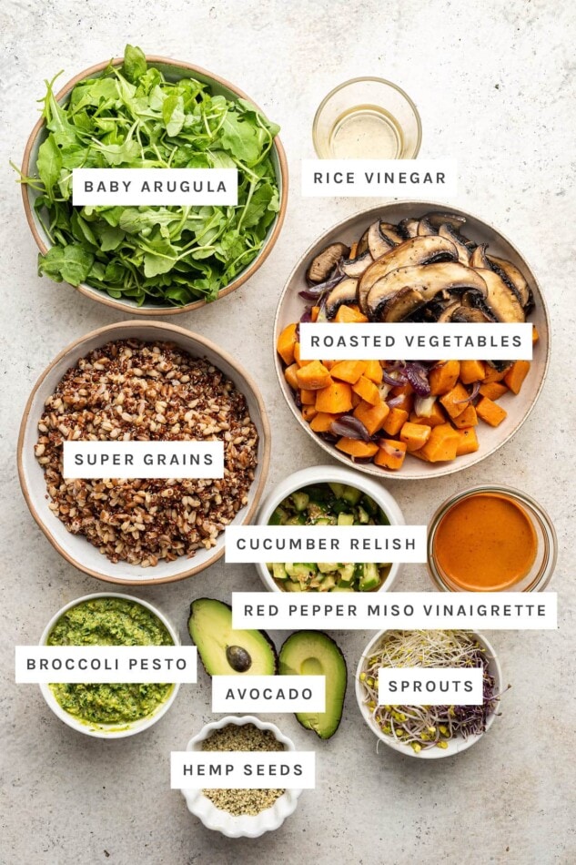 Ingredients measured out to make a Mother Earth Bowl: baby arugula, rice vinegar, roasted vegetables, super grains, cucumber relish, red pepper miso vinaigrette, broccoli pesto, avocado, sprouts and hemp seeds.