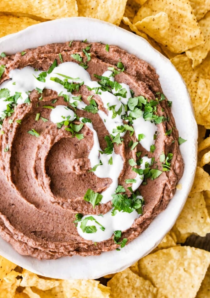 A bowl of black bean dip surrounded by tortilla chips.
