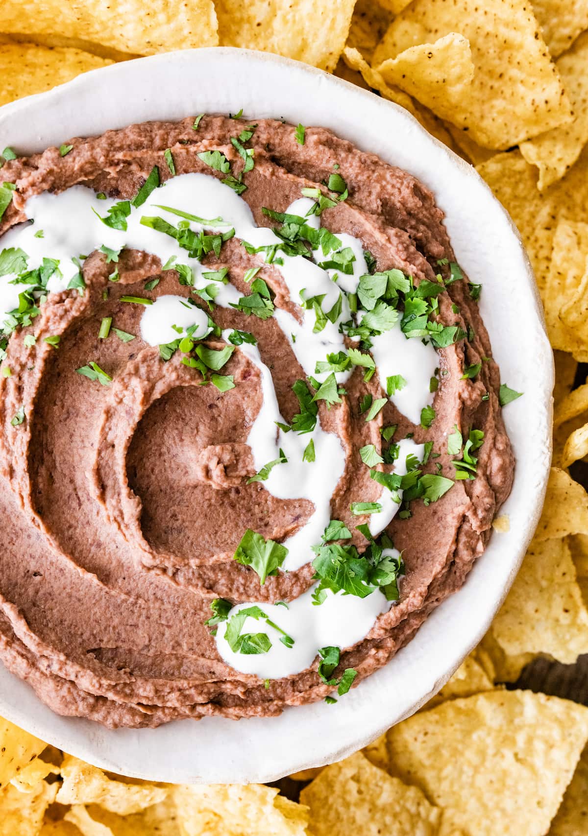 A bowl of black bean dip surrounded by tortilla chips.