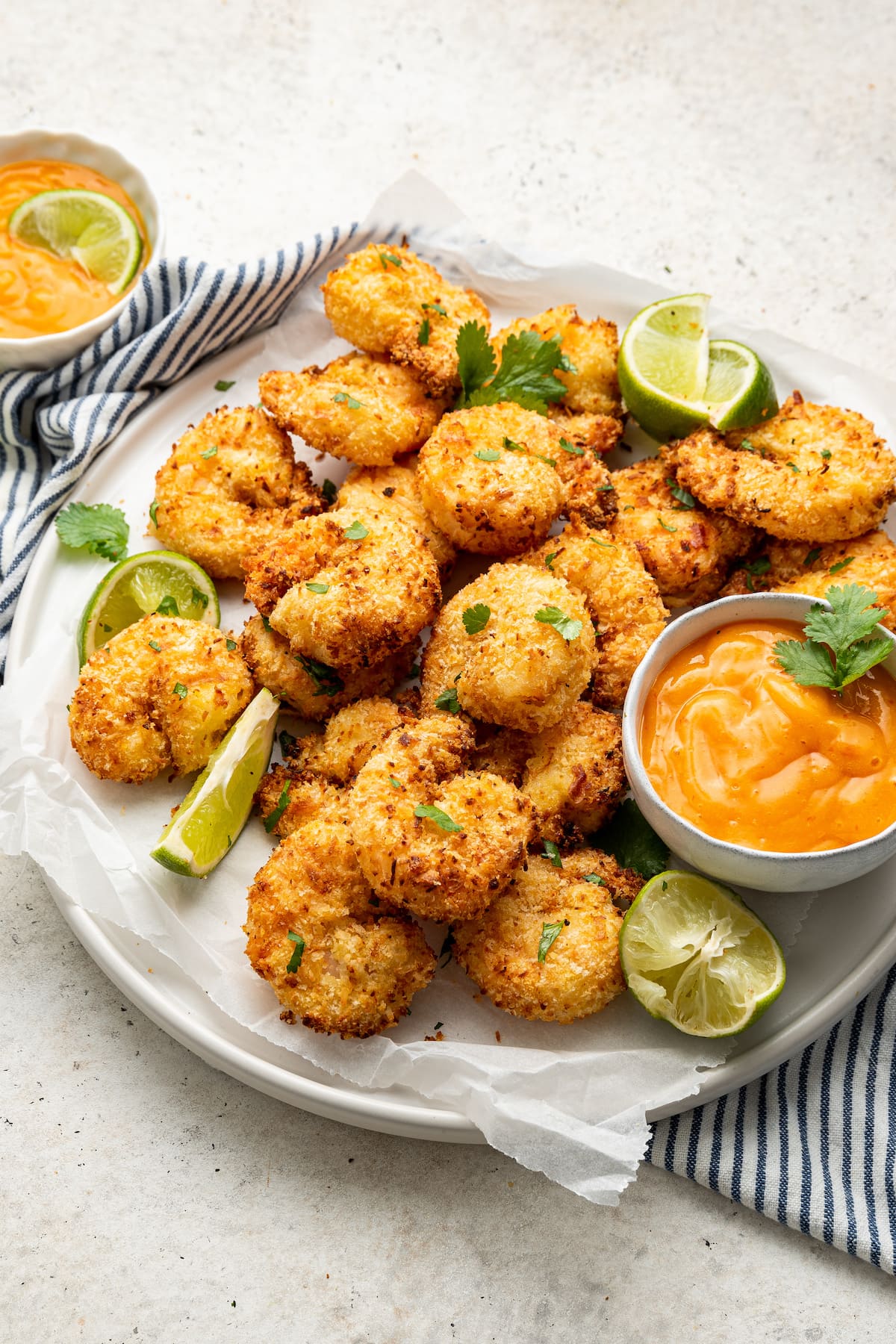 Air-fried coconut shrimp on a plate with dipping sauce.