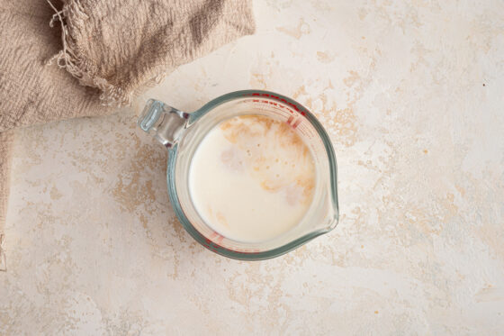 Vinegar and almond milk in a glass measuring cup.
