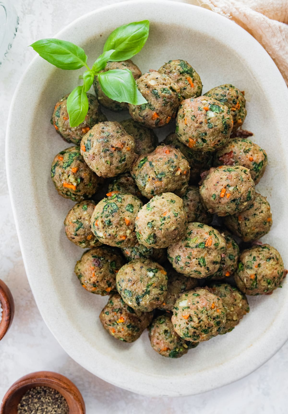 These simple clean eating Popeye turkey meatballs are moist and flavorful, loaded with veggies and require no binders! Great for meal prep because you can add them to pasta, sandwiches, salads and more throughout the week! Gluten-free, dairy-free, paleo. Spinach turkey meatballs on a serving platter.