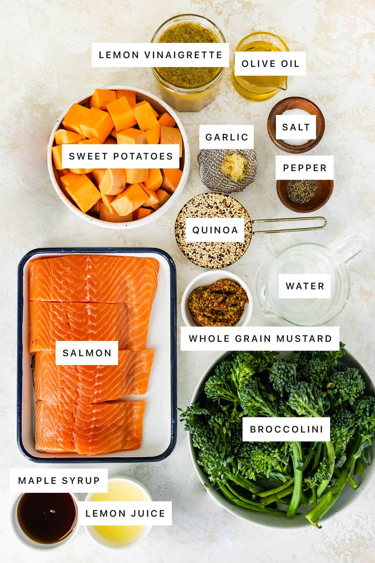 Ingredients measured out to make Easy Salmon Meal Prep Bowl: lemon vinaigrette, olive oil, sweet potatoes, garlic, salt, pepper, quinoa, water, whole grain mustard, salmon, broccolini, maple syrup and lemon juice.
