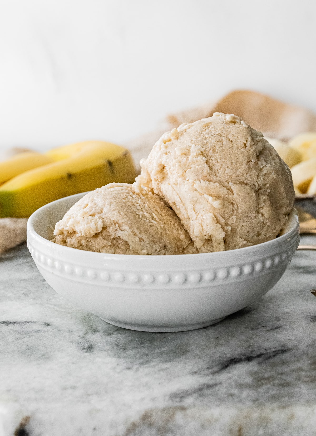 White bowl with two scoops of banana frozen yogurt.