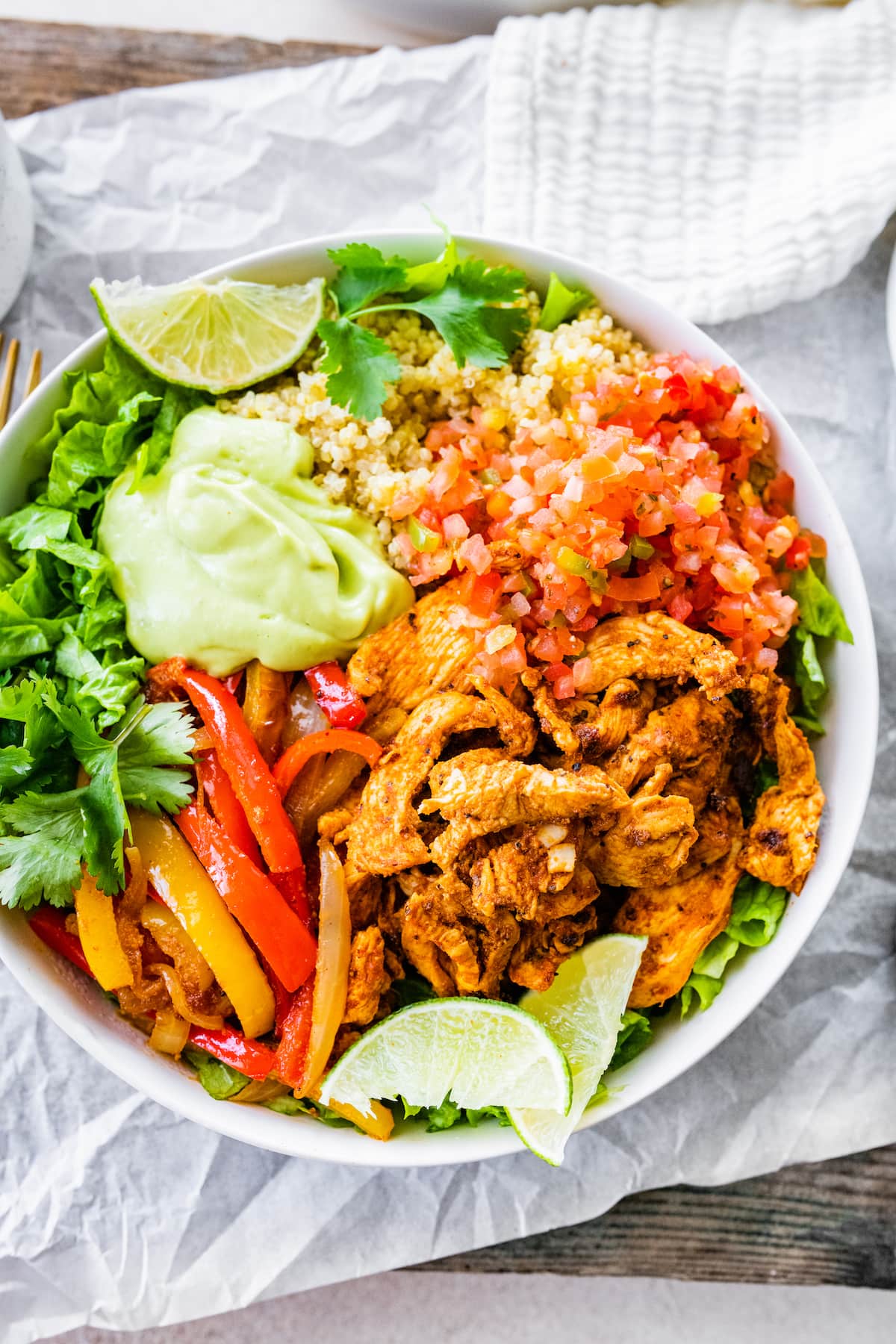 Make Mexican night fun and healthy with these chicken fajita quinoa bowls featuring spiced-up chicken, sautéed peppers and a creamy avocado goat cheese sauce. One chicken fajita bowl, topped with pico de gallo, avocado sauce, fresh cilantro and lime wedges.