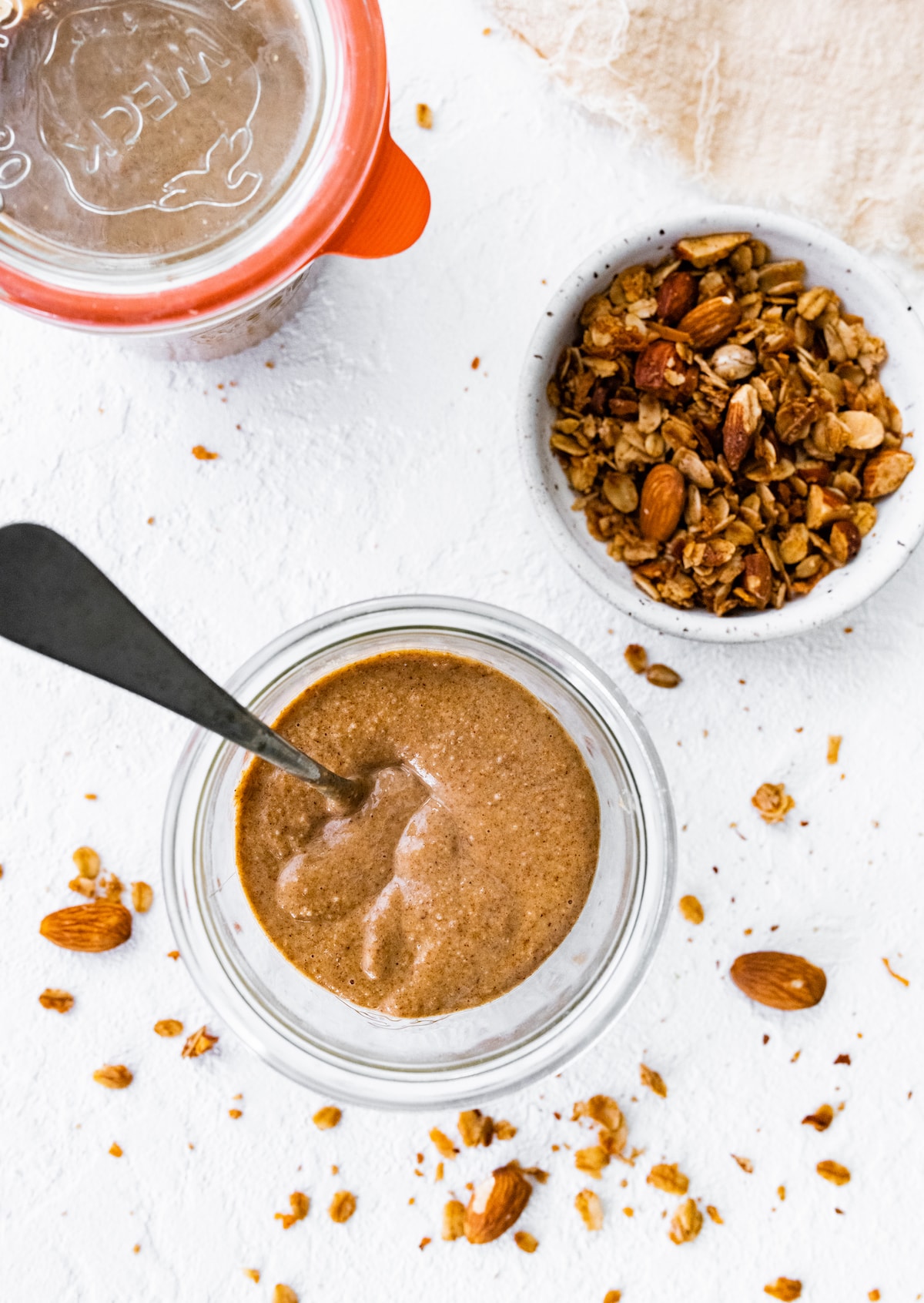 Overhead view of granola butter in a weck jar with a spoon in it.