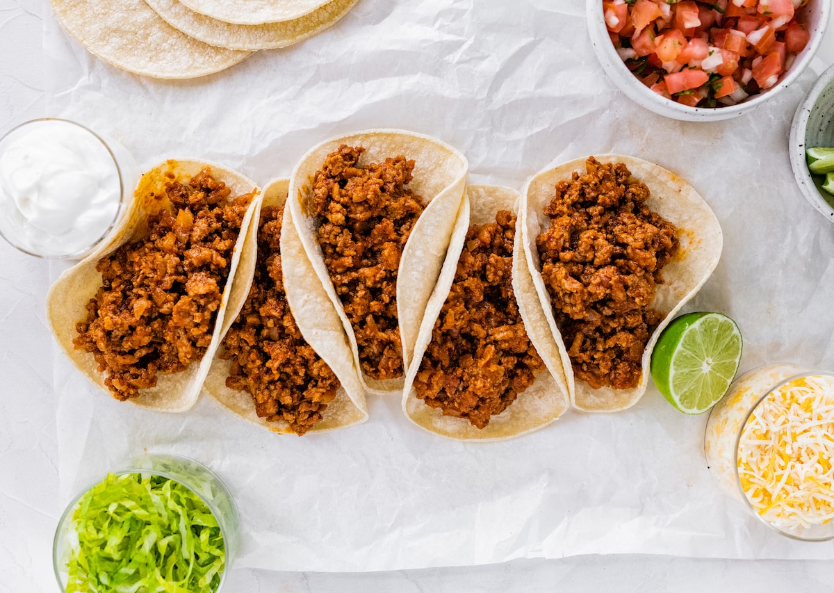 Five ground turkey tacos in tortillas without toppings.