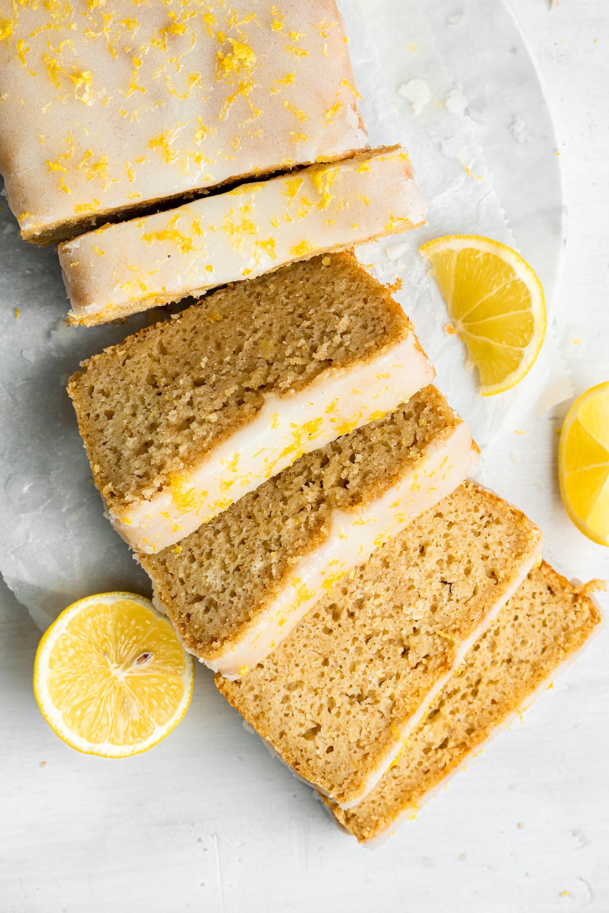 An overhead image of a lemon loaf topped with a lemon glaze cut into 5 slices