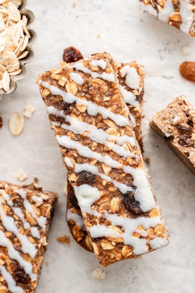 These cinnamon oatmeal raisin protein bars taste like an oatmeal raisin cookie drizzled with dark chocolate. They're great as a pre-workout snack and also make for an energizing on-the-go breakfast option for busy mornings. Close up image of one oatmeal raisin protein bar with coconut butter drizzle.