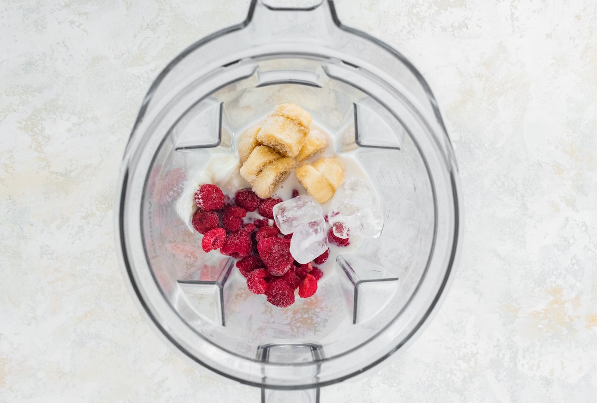 Raspberry smoothie ingredients in blender.