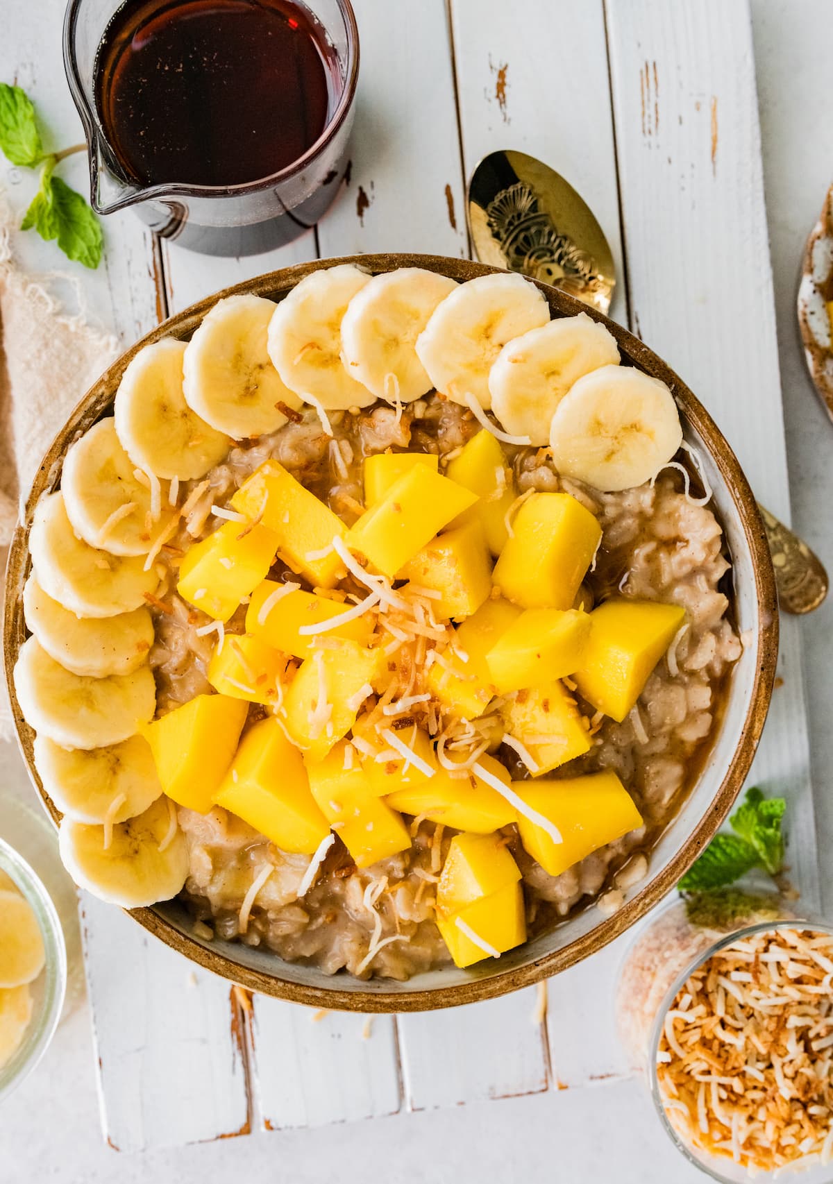 A healthy bowl of oats that will have you daydreaming about tropical islands and white sandy beaches. Bowl of oatmeal topped with fresh mango, banana slices and toasted coconut.