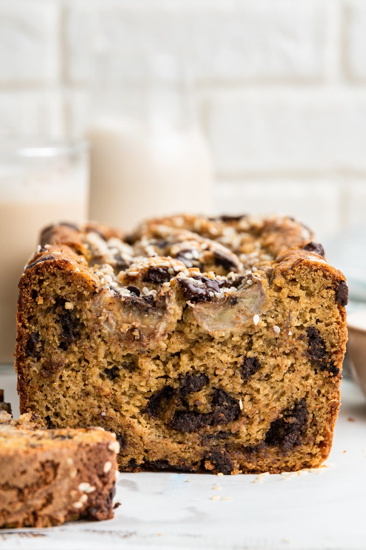 A straight-on image of a loaf of tahini banana bread with one sliced piece to the side.