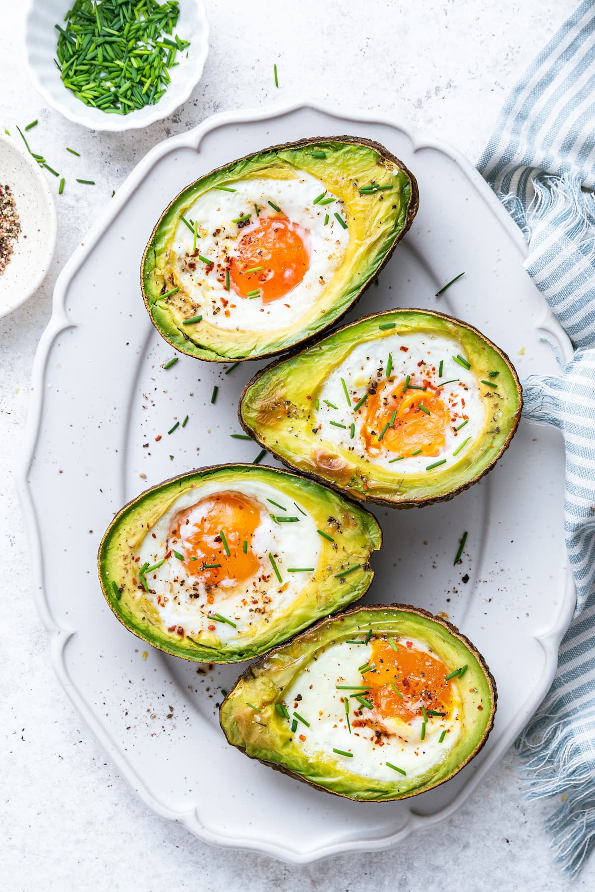 _MG_0370.jpg Four avocado halves served on a plate with a baked egg in the center of each.