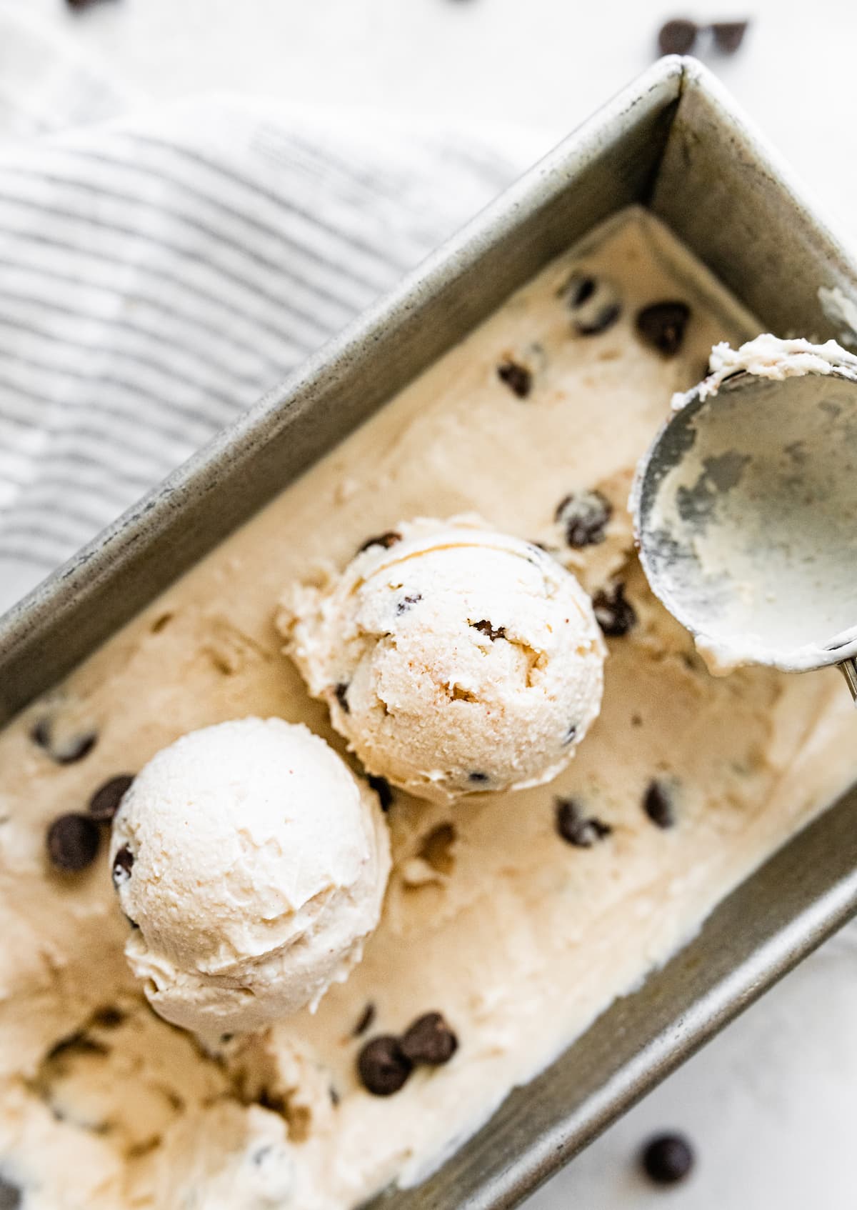 Ice cream scoop scooping cottage cheese ice cream from loaf pan.
